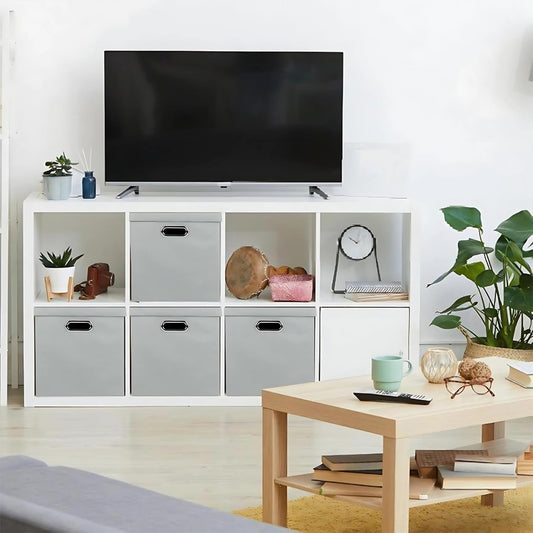 Modern living room with a TV on a white entertainment console, coffee table, and decorative items.