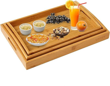 Bamboo tray with food items including a glass of juice, fruits, and snacks on a white background.