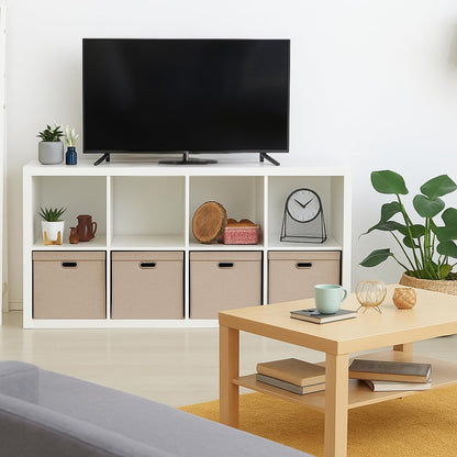 Modern living room with a TV on a white entertainment console, coffee table, and decorative items including foldable storage boxes.