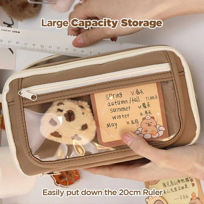 Close-up of a large capacity pencil case with a clear pocket holding a plush cookie and note. A practical pencil box for essentials.
