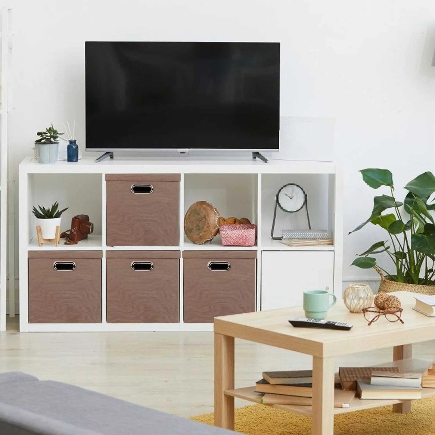 Brown foldable storage boxes organizing a modern living room shelf. Ideal folding storage solution.